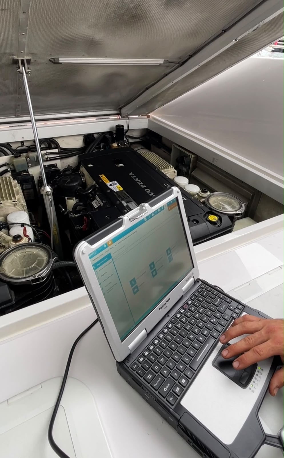VO Marine engineer running diagnostics on a Volvo Penta engine in a yacht engine bay